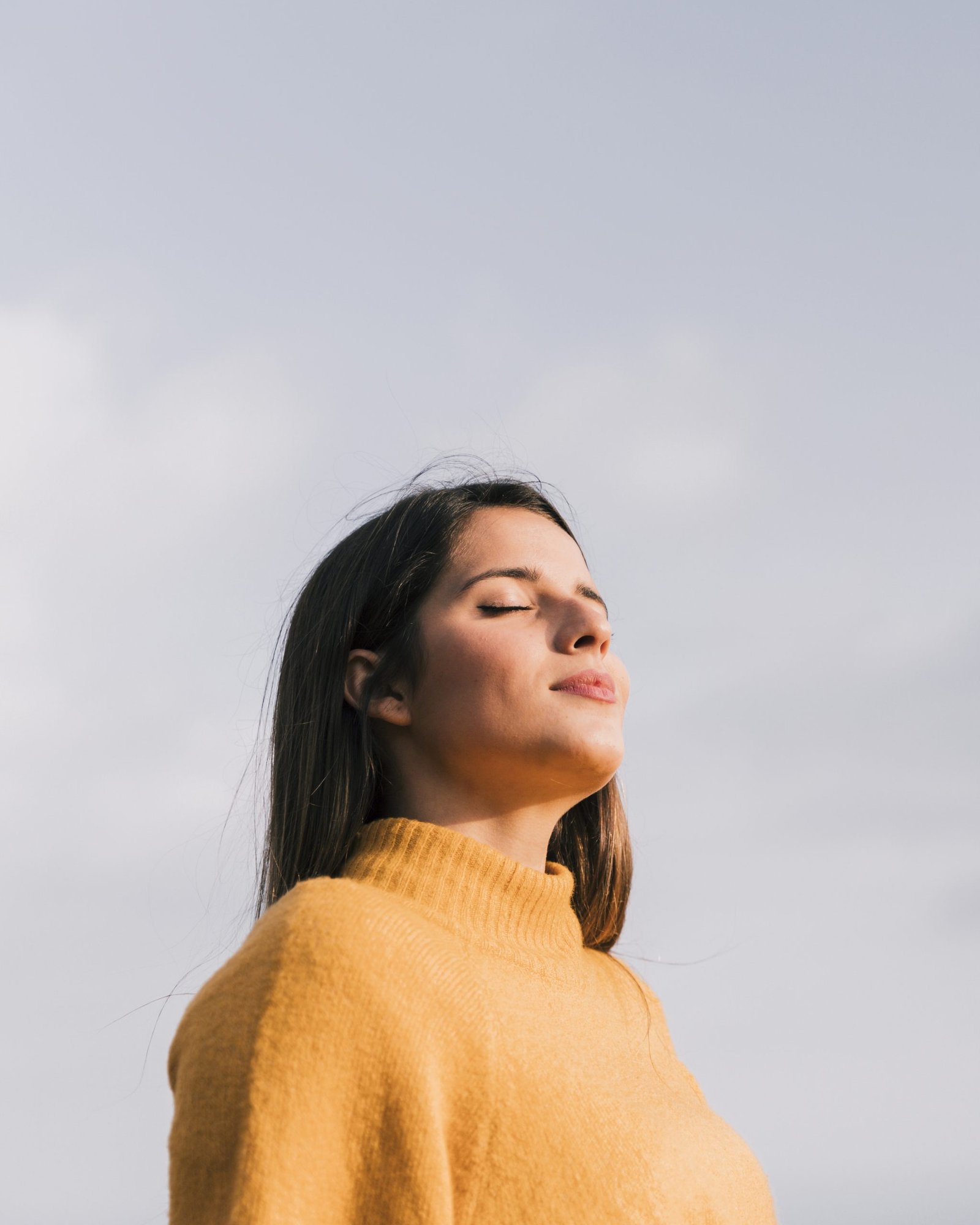 portrait young woman with her closed eyes standing against blue sky scaled